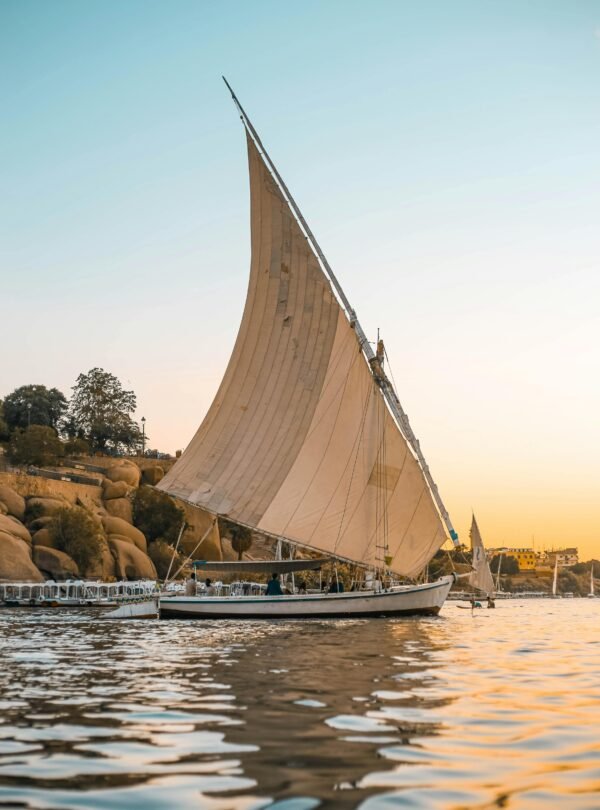 Scenic view of a traditional Egyptian felucca sailing at sunset on the Nile.